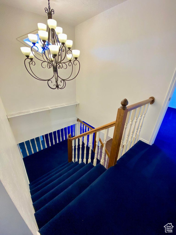 Stairs with a notable chandelier and carpet