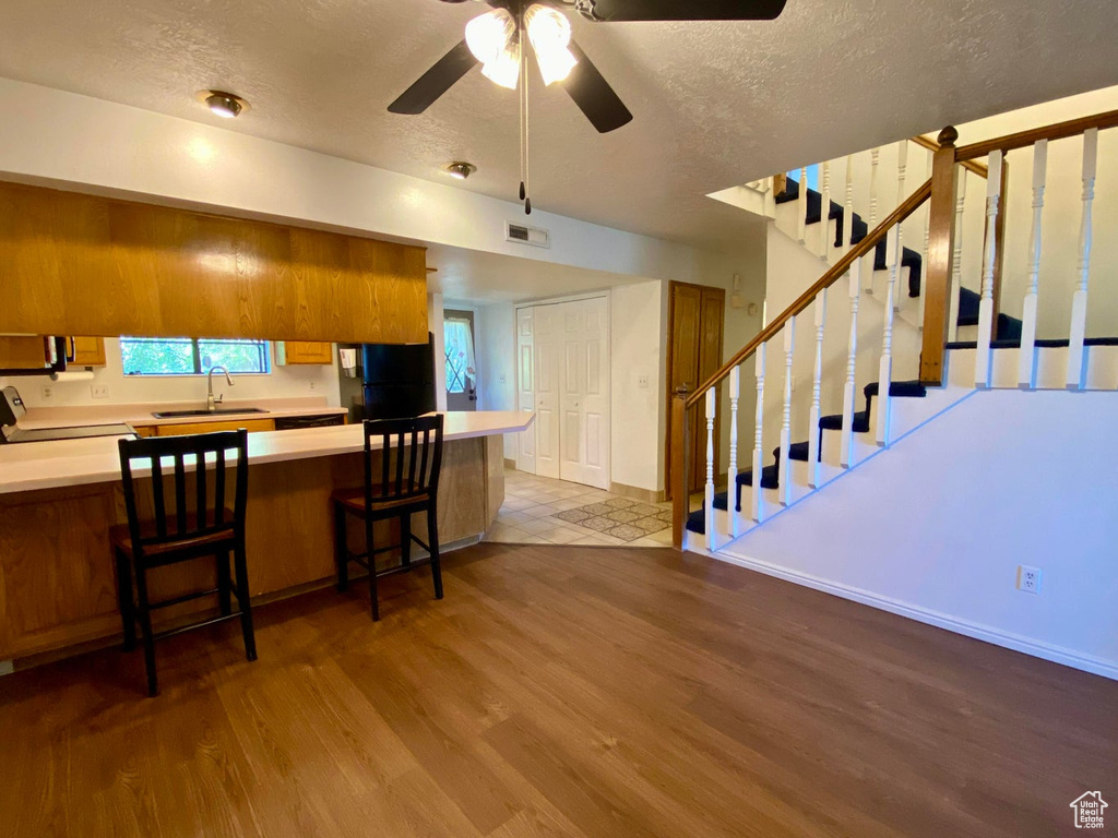 Kitchen featuring range, a breakfast bar area, light hardwood / wood-style floors, kitchen peninsula, and sink