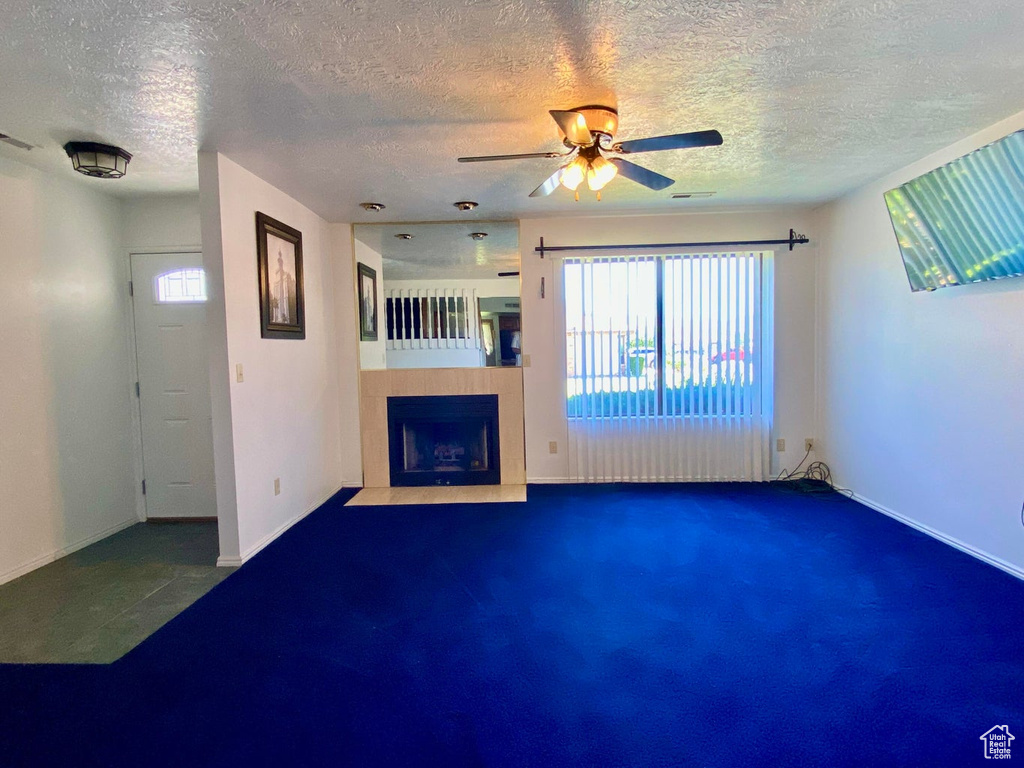 Unfurnished living room featuring a textured ceiling and ceiling fan