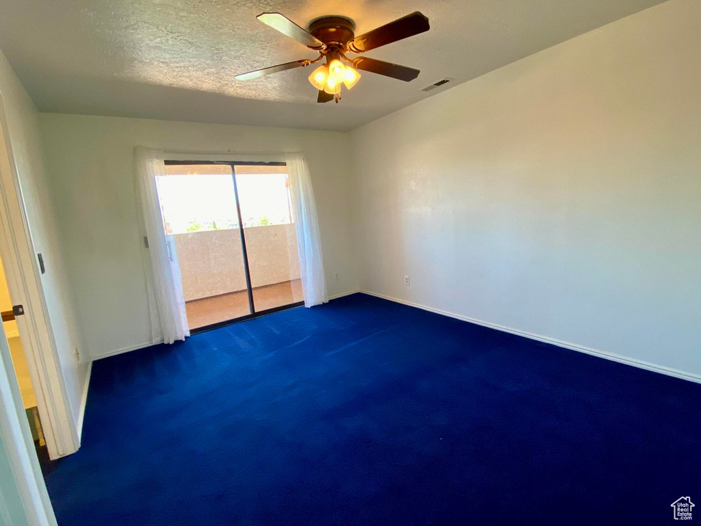 Carpeted empty room with a textured ceiling and ceiling fan
