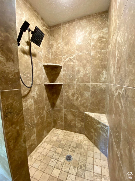Bathroom featuring a tile shower and a textured ceiling