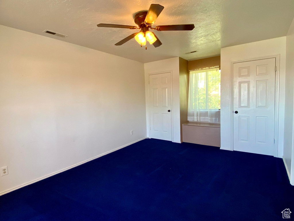 Unfurnished bedroom featuring ceiling fan, carpet, and a textured ceiling