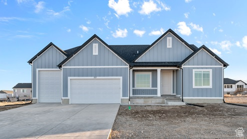 View of front of property with an attached garage, board and batten siding, and concrete driveway