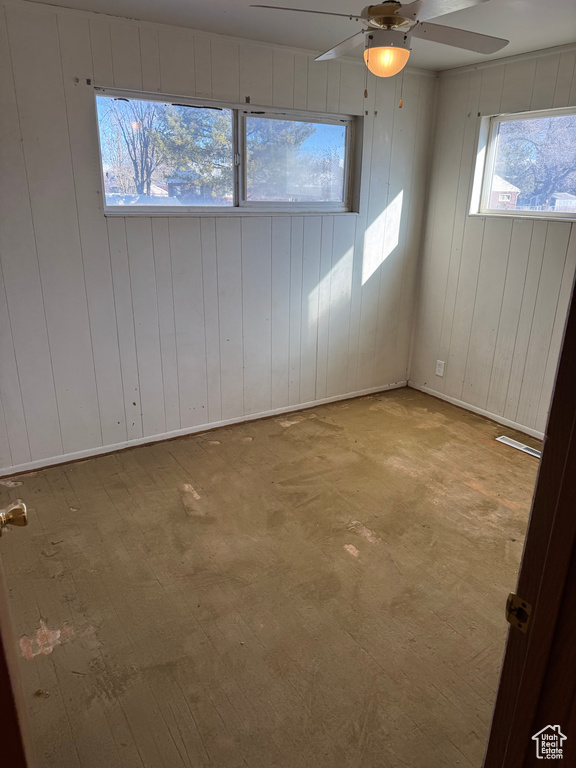 Empty room with ceiling fan and wood walls