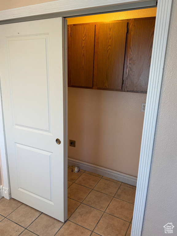 Laundry area featuring light tile patterned flooring and cabinets
