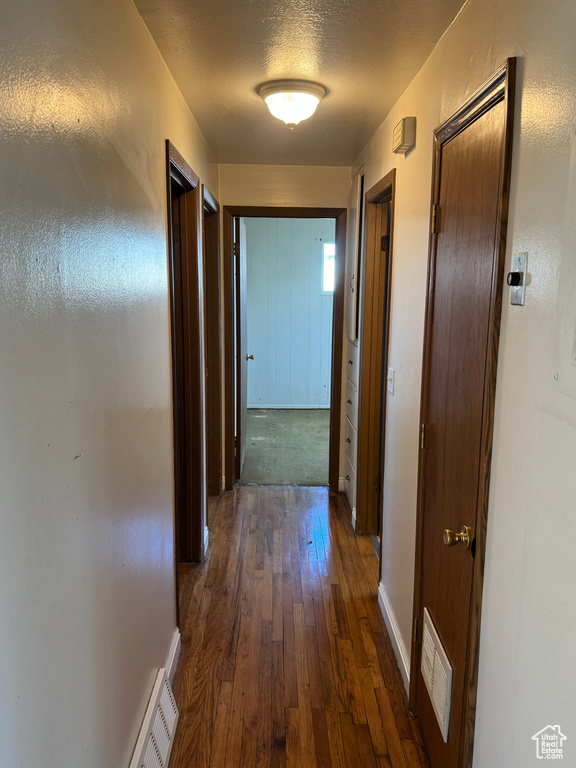 Corridor with dark hardwood / wood-style floors and a textured ceiling