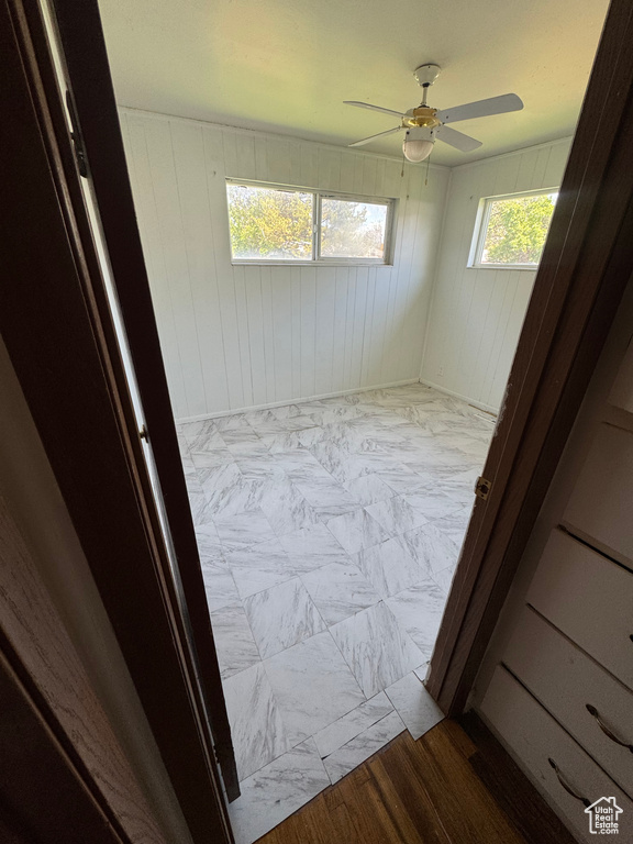 Empty room featuring a ceiling fan and wood walls