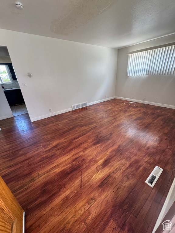Empty room with wood finished floors, a smoke detector, and baseboards