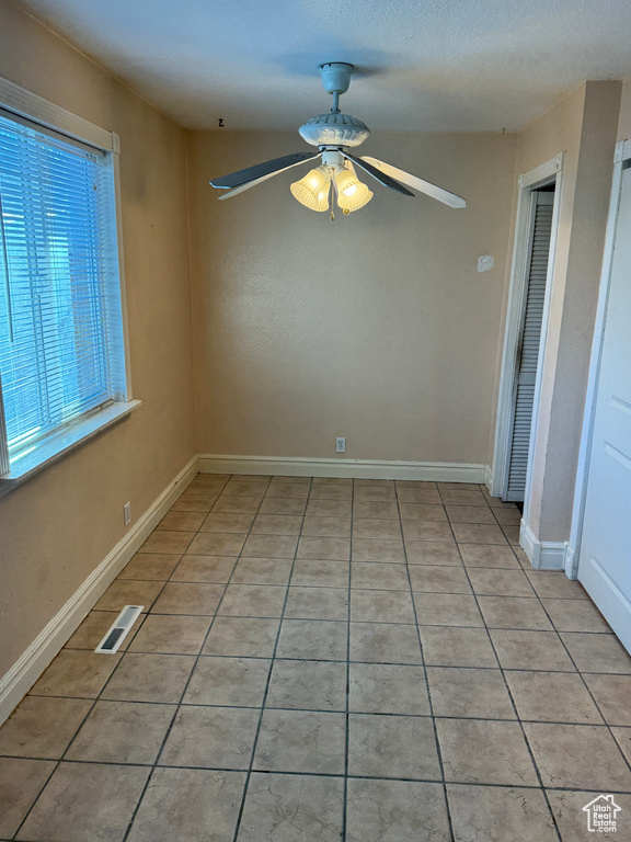 Empty room featuring ceiling fan and light tile patterned flooring
