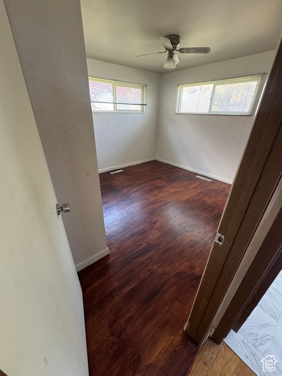 Unfurnished room with baseboards, a ceiling fan, wood finished floors, and a textured wall
