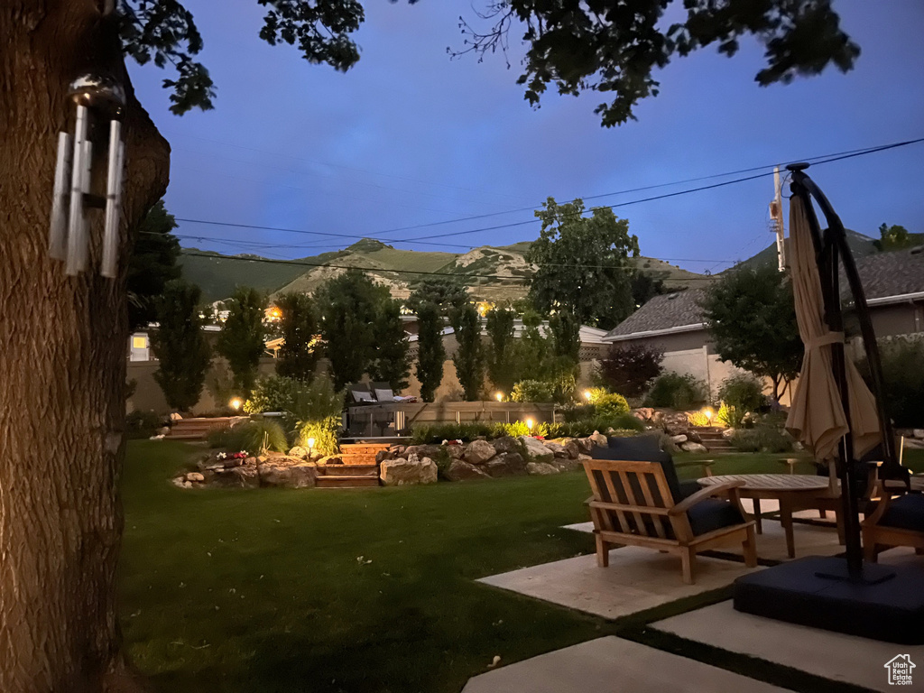 Yard at dusk with a mountain view and a patio