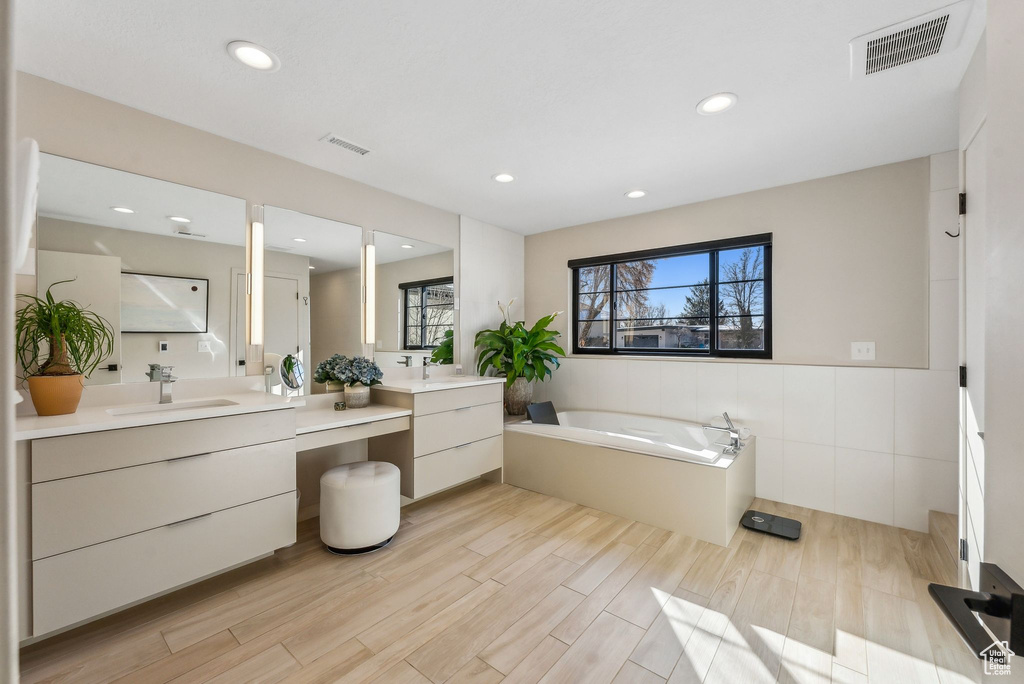 Bathroom featuring vanity, a tub, and tile walls