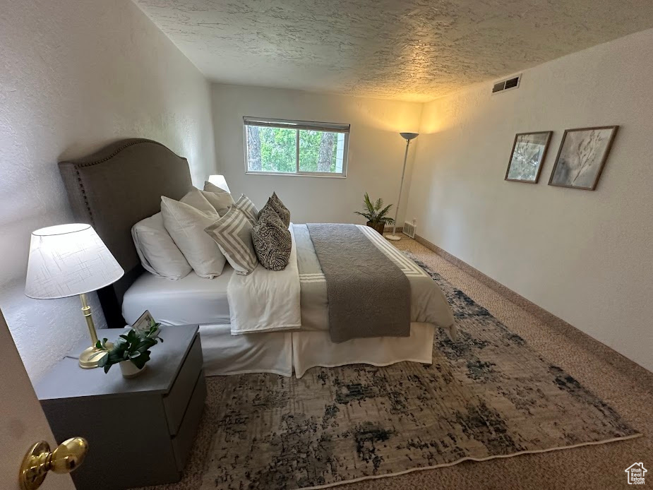 Bedroom with a textured ceiling and carpet flooring