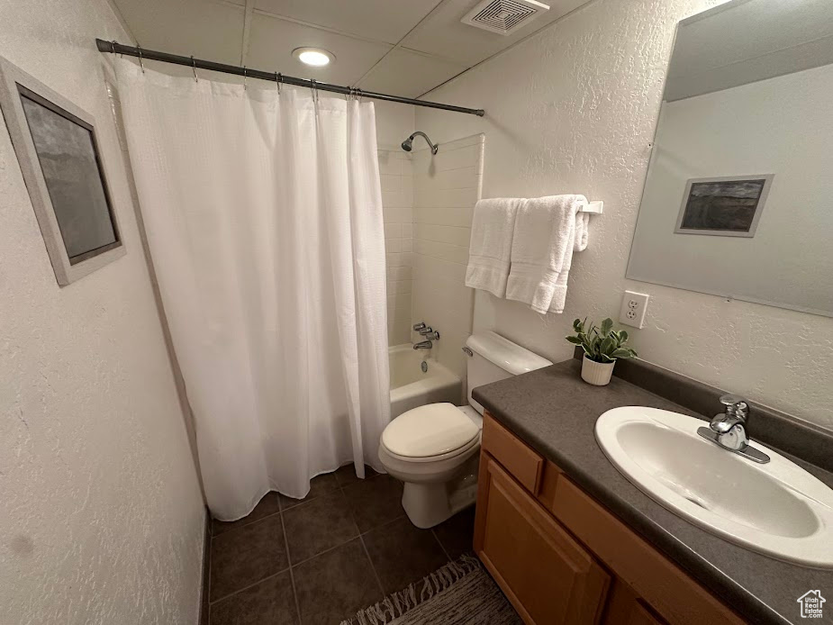 Full bathroom with a textured wall, vanity, toilet, tile patterned flooring, and shower / bath combination with curtain