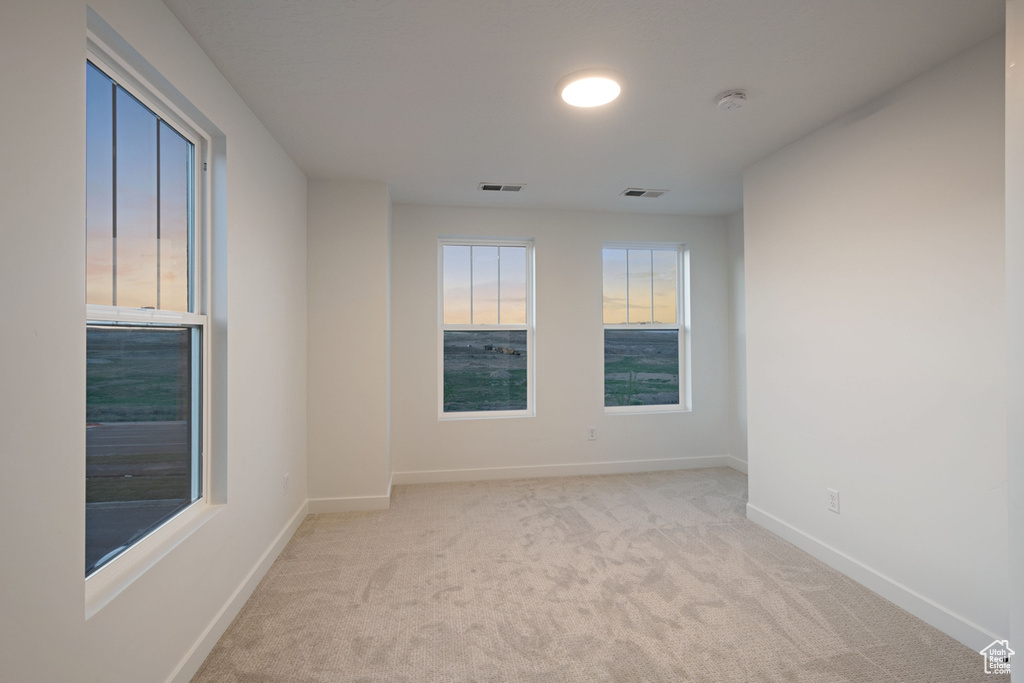 Unfurnished room featuring light colored carpet, baseboards, and a smoke detector