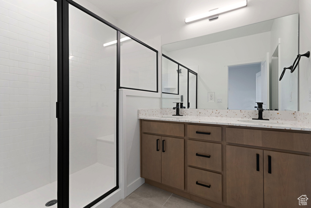 Bathroom featuring a stall shower, double vanity, and tile patterned flooring