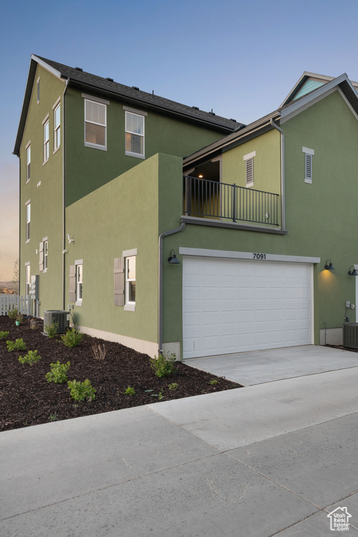 View of front of home featuring a garage, stucco siding, concrete driveway, and cooling unit