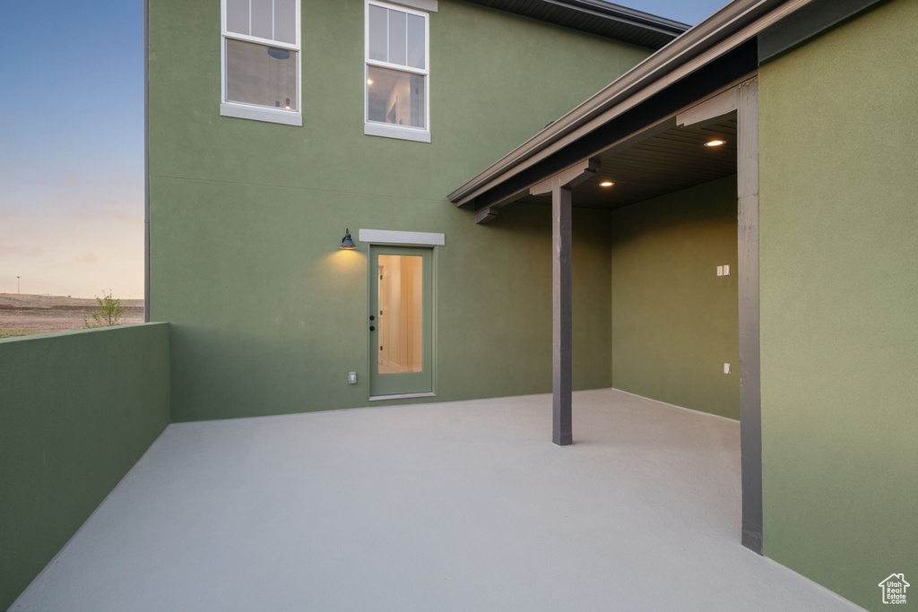 Back of house at dusk with stucco siding and a patio area