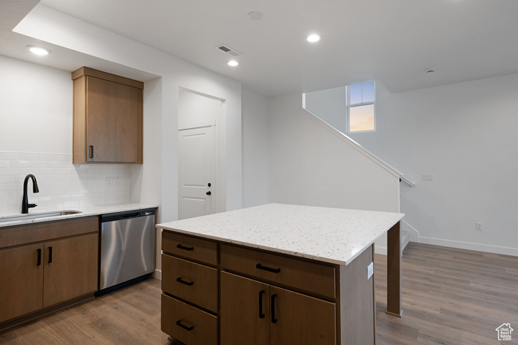 Kitchen featuring dishwasher, a sink, dark wood-type flooring, decorative backsplash, and recessed lighting