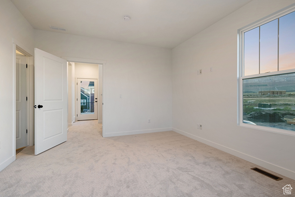 Empty room with light colored carpet, baseboards, and a smoke detector