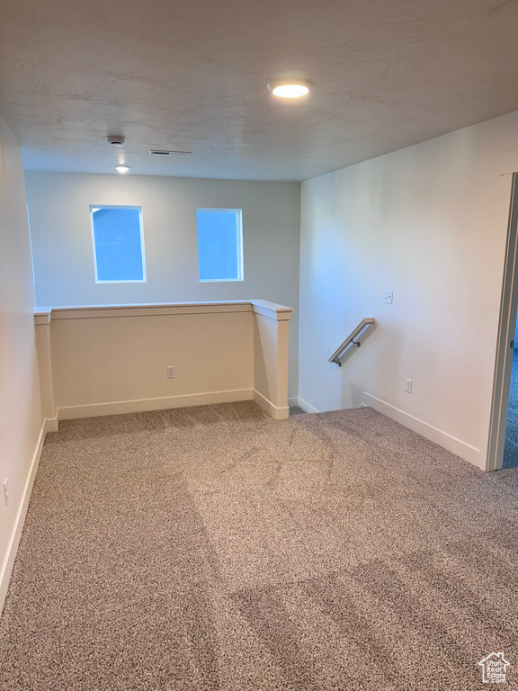 Empty room with carpet flooring and a textured ceiling