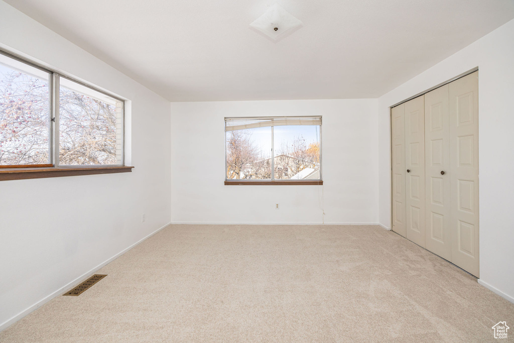 Unfurnished bedroom featuring light carpet and a closet