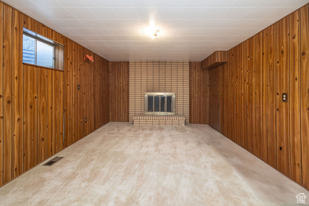 Basement with carpet flooring, wooden walls, and a fireplace