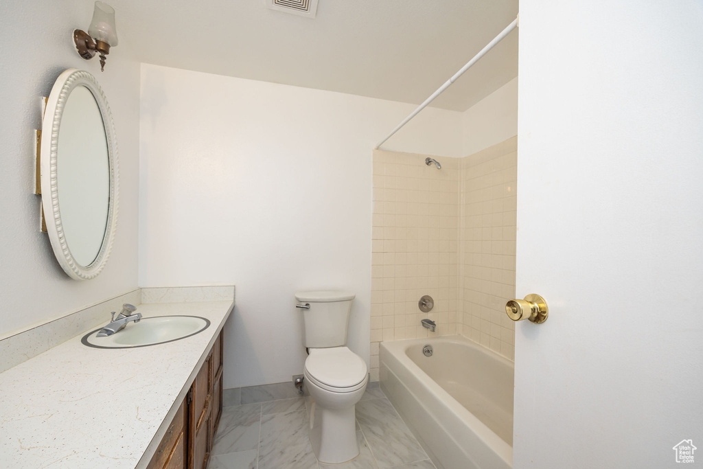 Full bathroom featuring toilet, vanity, and tiled shower / bath