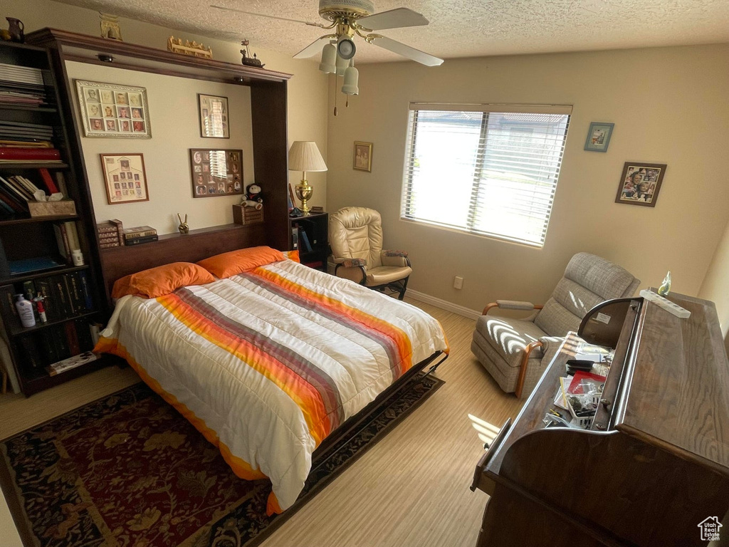Carpeted bedroom featuring a textured ceiling and ceiling fan