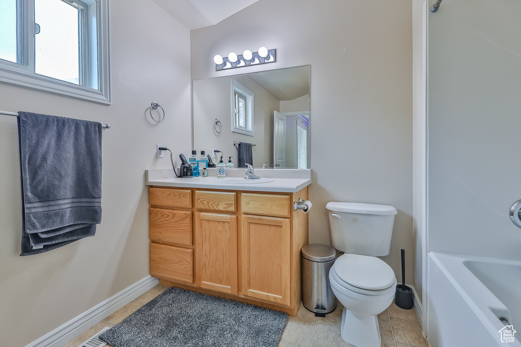Bathroom with toilet, vanity, tile patterned floors, and a wealth of natural light