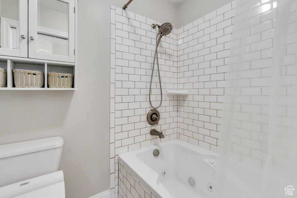 Bathroom with tiled shower / bath combo and toilet