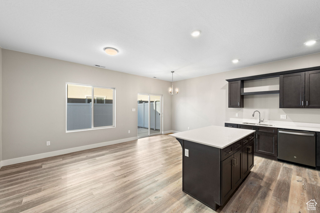 Kitchen with dishwasher, sink, a kitchen island, light wood-type flooring, and pendant lighting