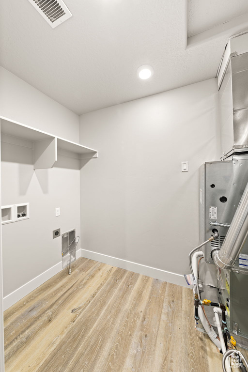 Clothes washing area featuring washer hookup, electric dryer hookup, and light hardwood / wood-style floors