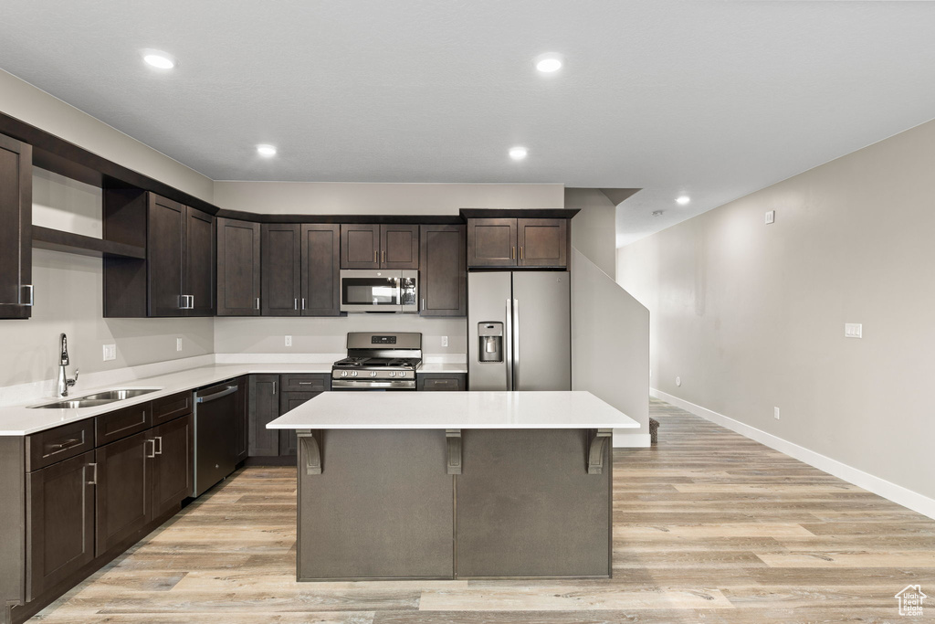 Kitchen with sink, appliances with stainless steel finishes, a center island, and a breakfast bar area