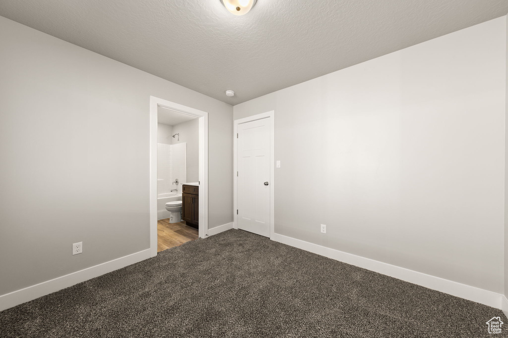 Unfurnished bedroom featuring a textured ceiling, carpet floors, and ensuite bathroom