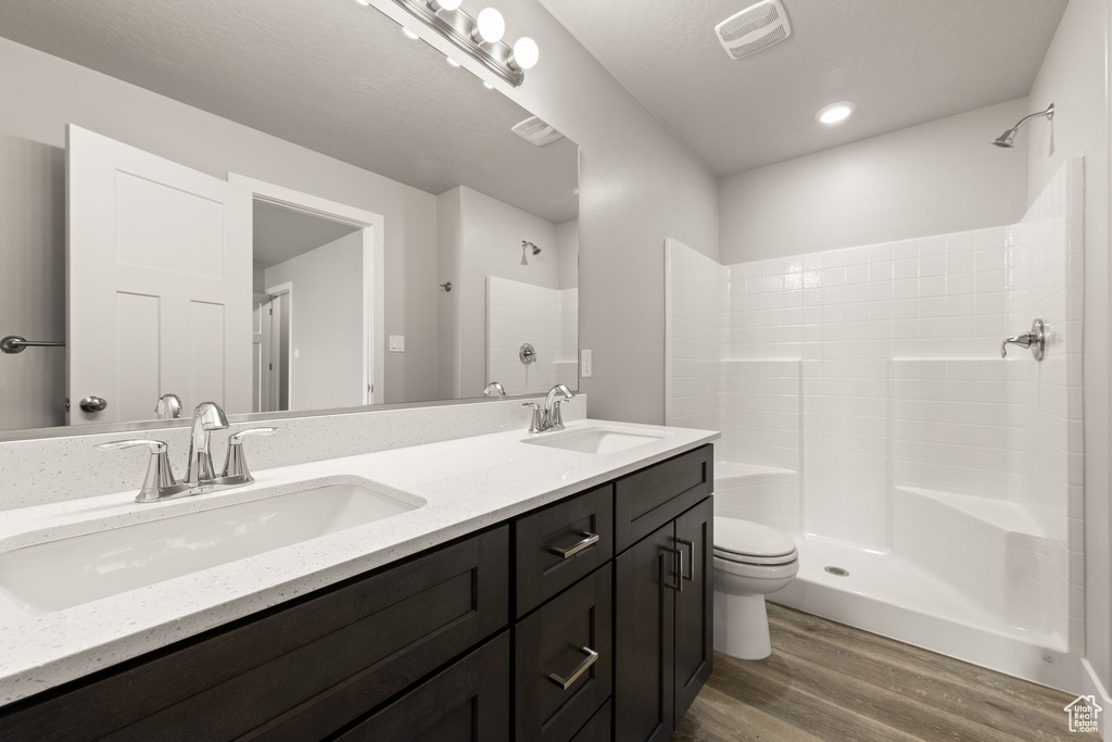 Bathroom featuring hardwood / wood-style flooring, a shower, toilet, and vanity