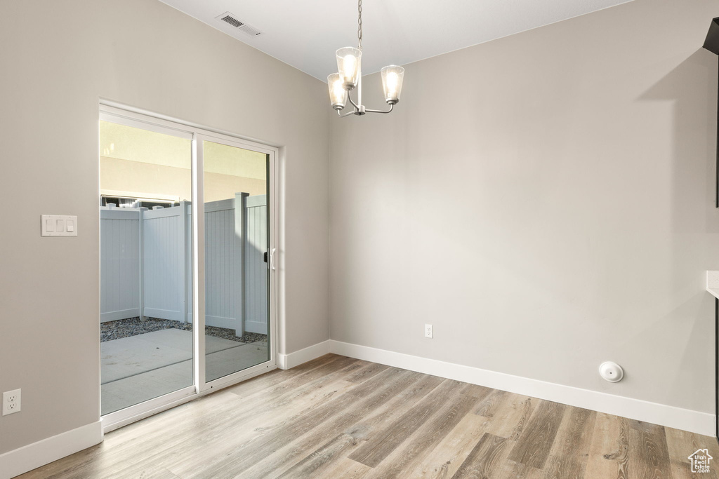 Spare room featuring light hardwood / wood-style floors and a chandelier