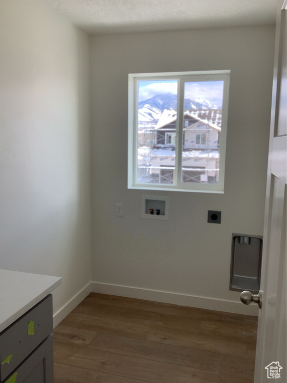 Washroom with hookup for a washing machine, wood finished floors, baseboards, hookup for an electric dryer, and laundry area