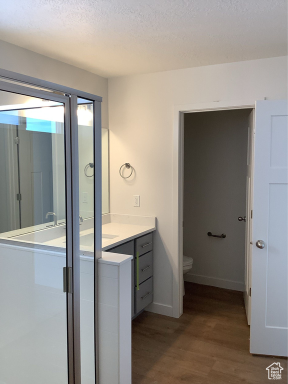 Full bathroom featuring toilet, a textured ceiling, wood finished floors, baseboards, and vanity