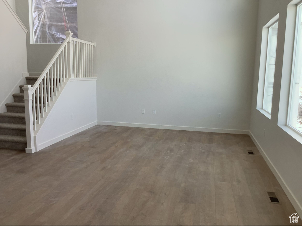 Empty room with visible vents, stairway, baseboards, and wood finished floors