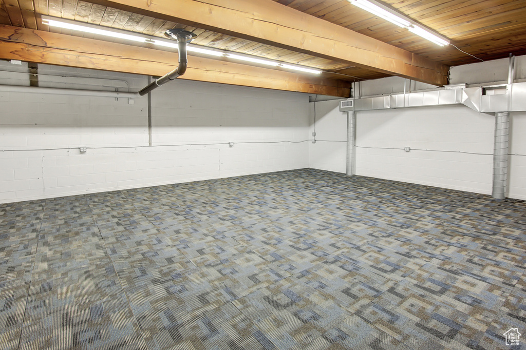 Basement featuring wood ceiling and dark colored carpet