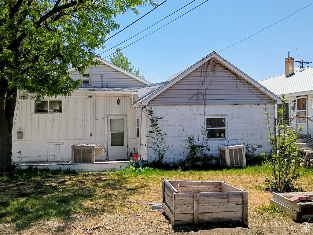Rear view of property featuring a vegetable garden, central AC, and fence