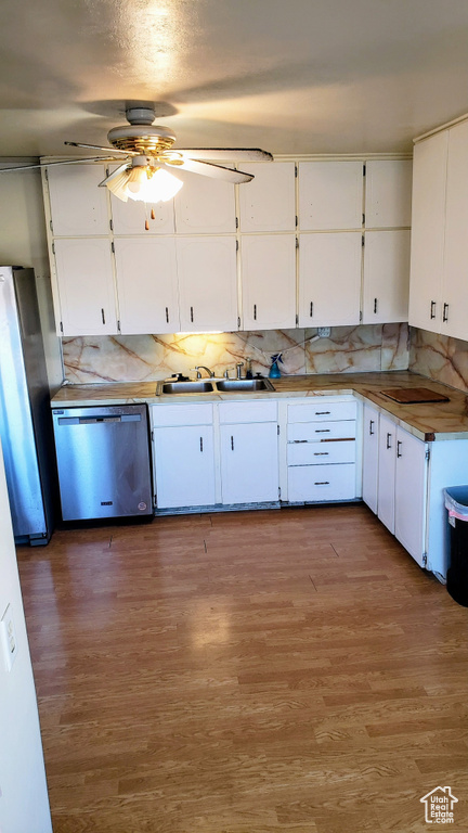 Kitchen featuring appliances with stainless steel finishes, a sink, a ceiling fan, white cabinetry, and decorative backsplash