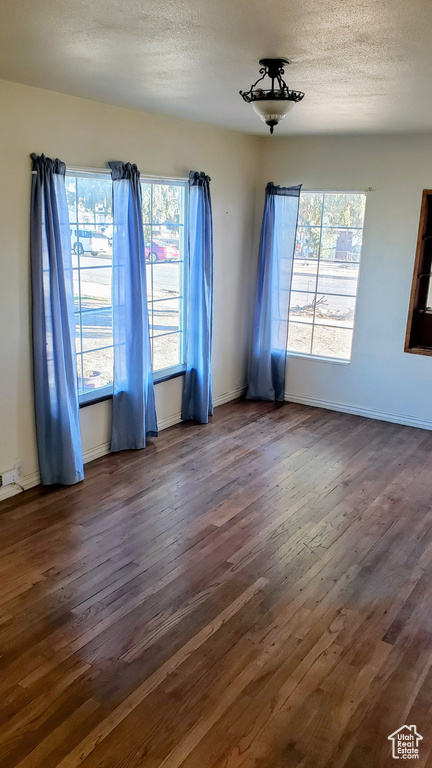 Spare room with dark wood finished floors, a textured ceiling, and baseboards