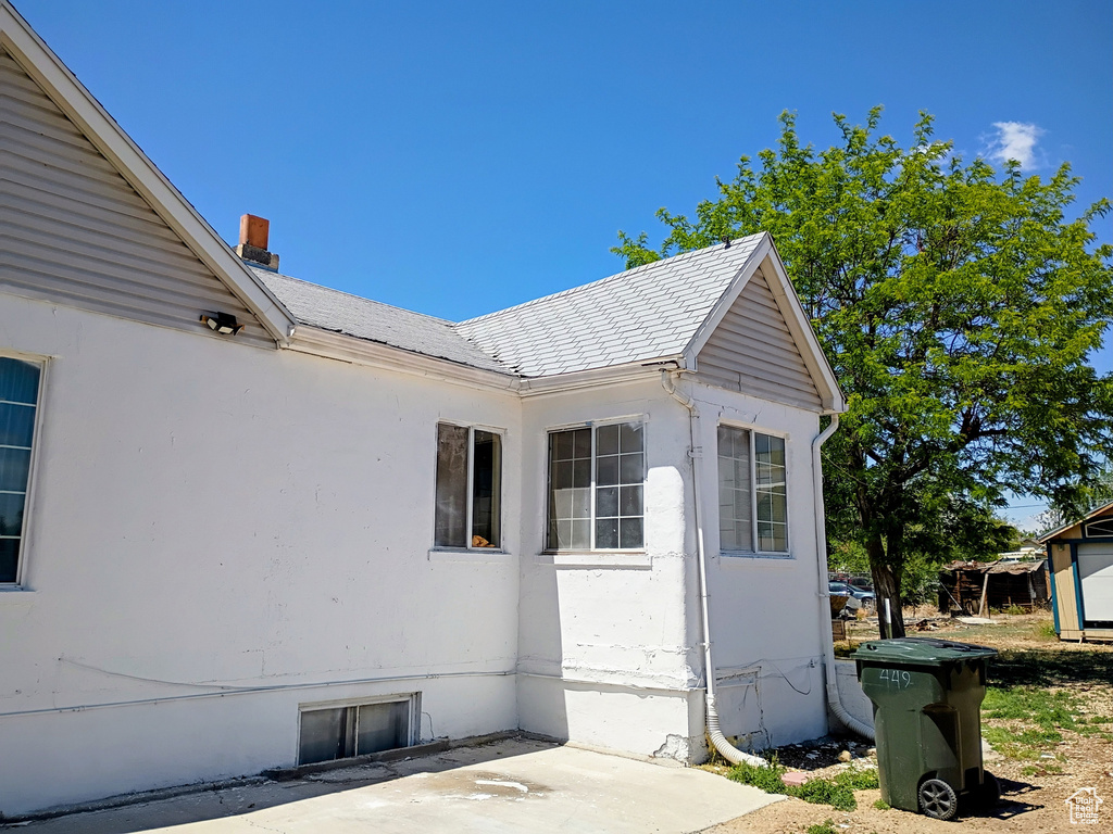 View of property exterior featuring a patio, a chimney, and stucco siding