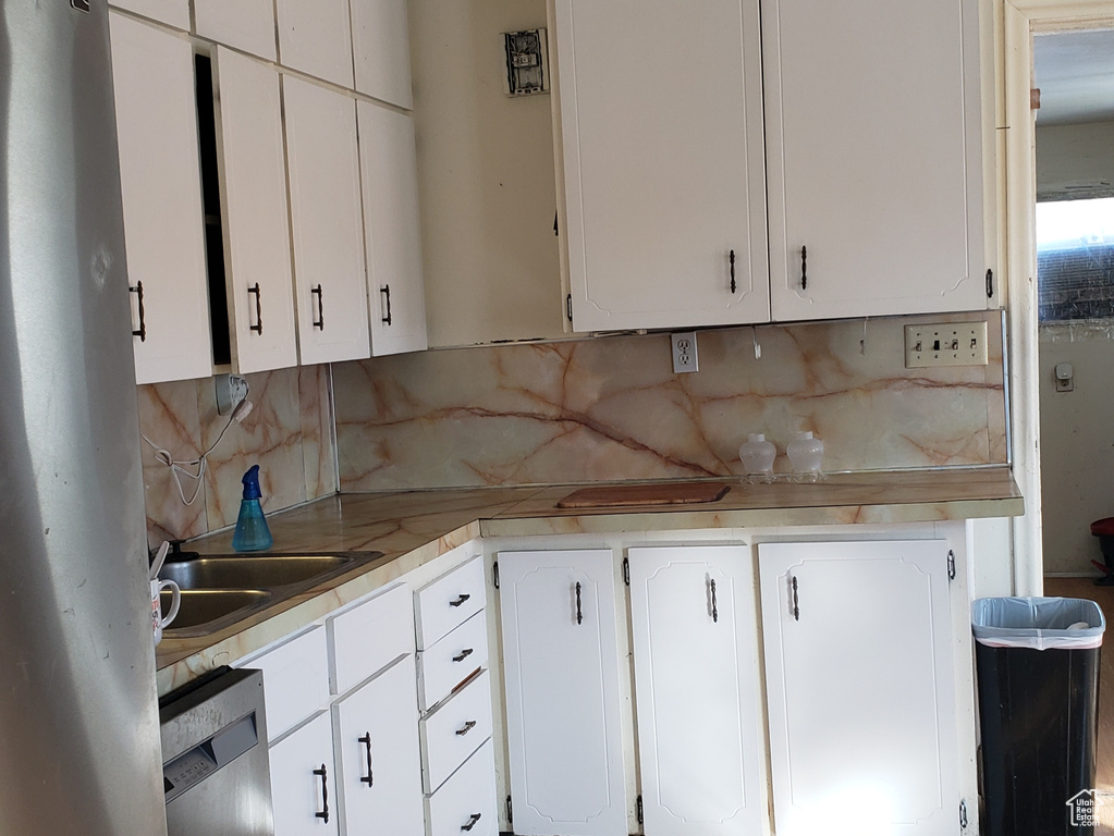 Kitchen featuring decorative backsplash, light hardwood / wood-style flooring, stainless steel appliances, and white cabinets