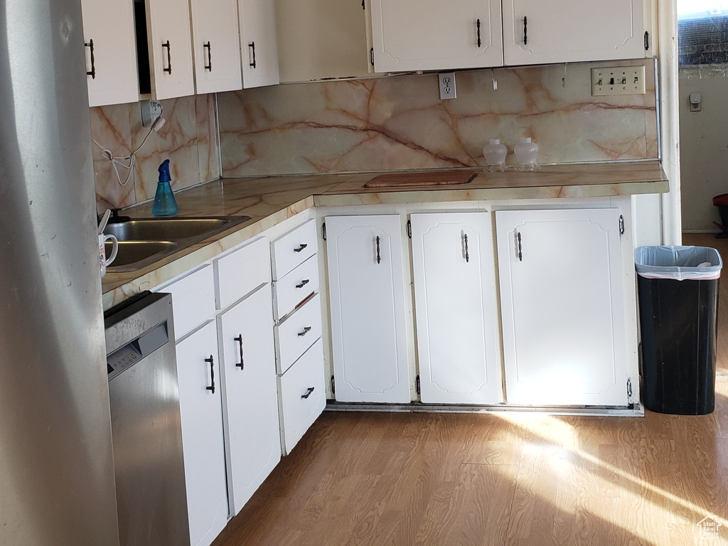Kitchen featuring stainless steel appliances, white cabinets, light countertops, and light wood finished floors