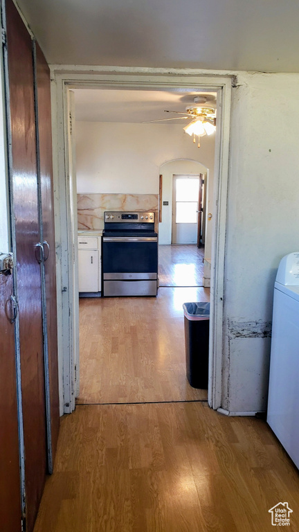 Hallway with washer / clothes dryer, light wood finished floors, and arched walkways