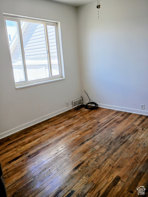 Empty room featuring dark wood-style flooring and baseboards