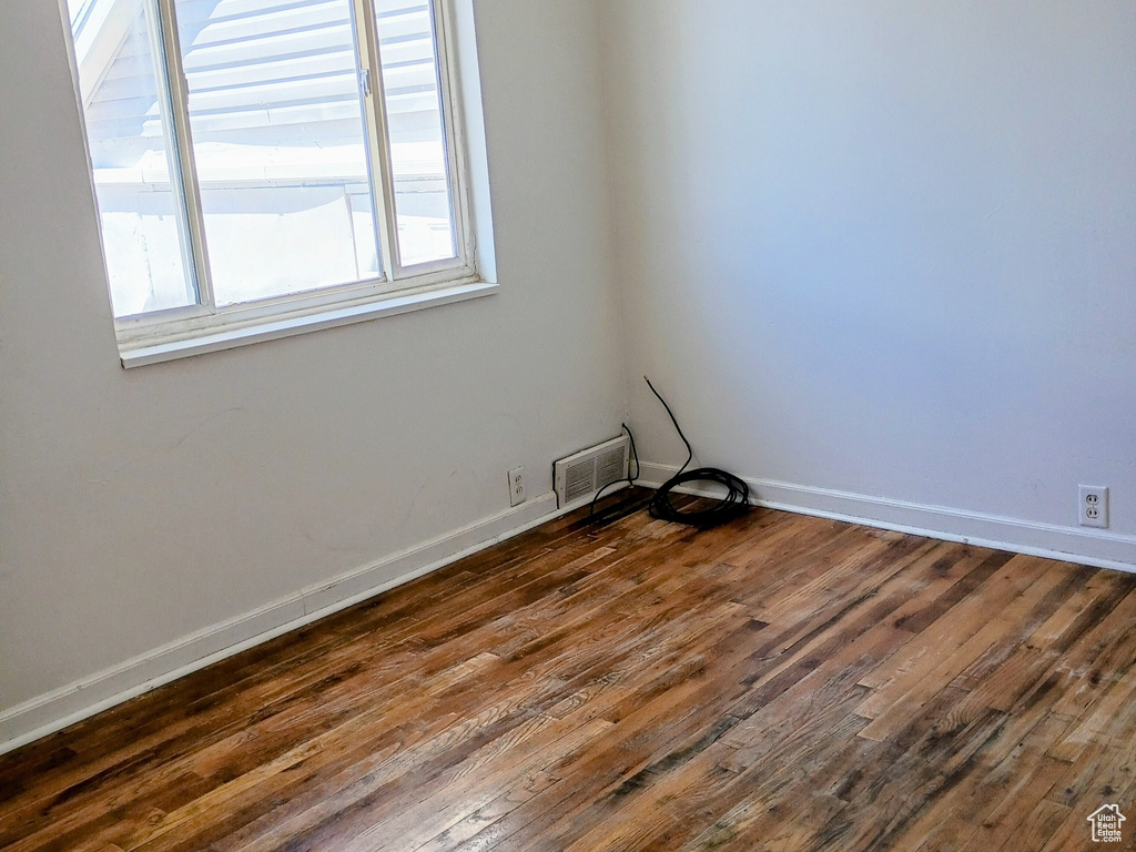 Empty room featuring dark wood-style flooring and baseboards